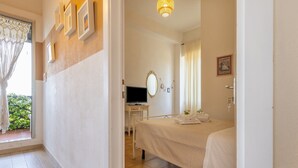 Une chambre à coucher avec un lit, un bureau avec une télévision, un miroir et une fenêtre avec des rideaux.