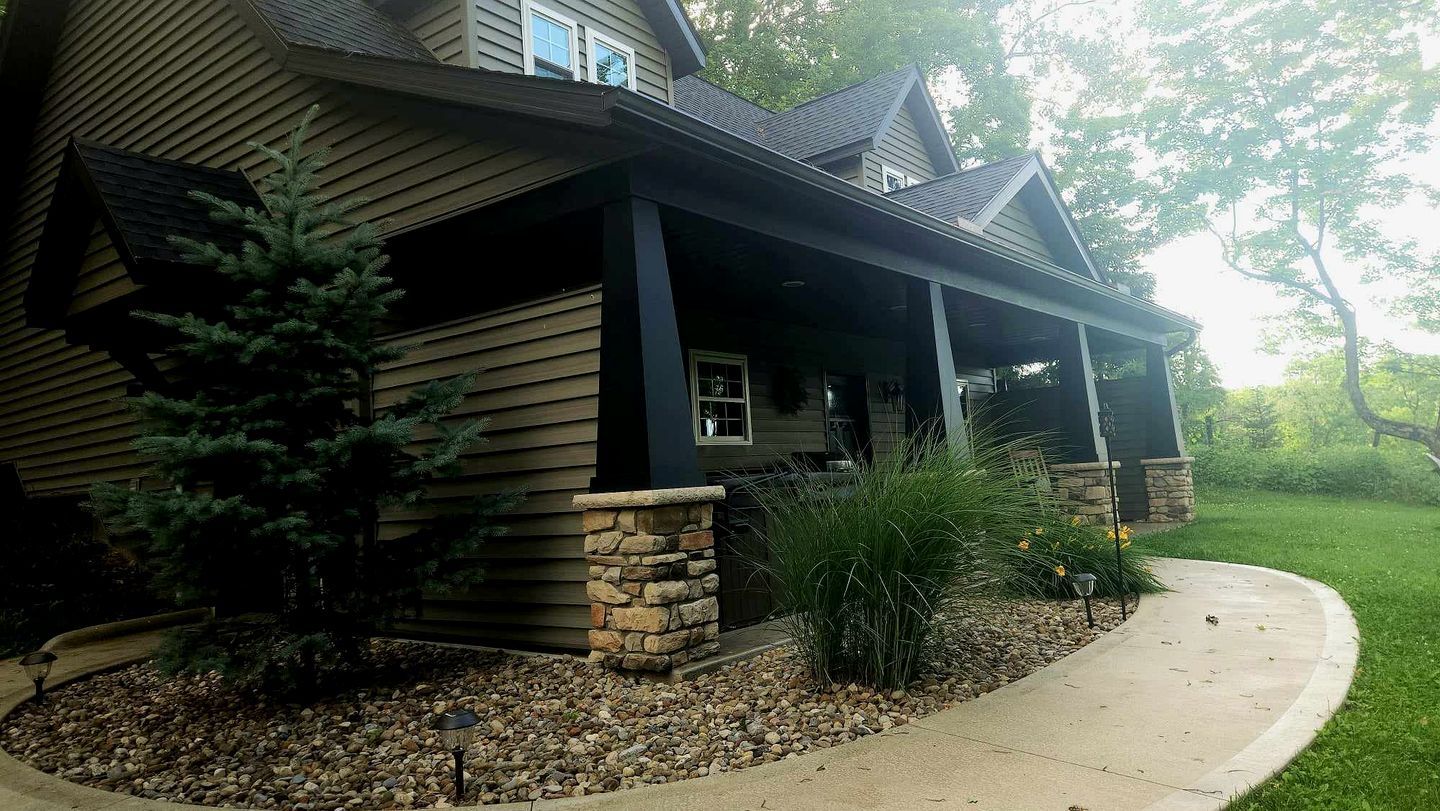 A house with a covered porch, stone accents, and a landscaped garden with a pathway.