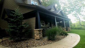 A house with a covered porch, stone accents, and a landscaped garden with a pathway. - Sweet Private Cabin with Jacuzzi and Fire Pit in Ohio (Sugarcreek)
