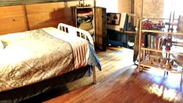 A bedroom with a bed, wooden wardrobe, and a bookshelf.