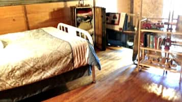A bedroom with a bed, wooden wardrobe, and a bookshelf.