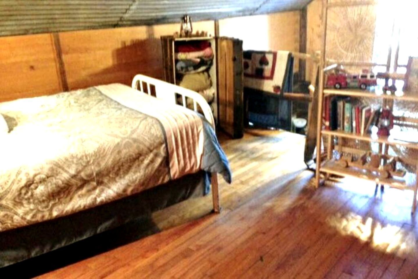 Een slaapkamer met een bed, een houten garderobe en een boekenkast.