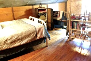 A bedroom with a bed, wooden wardrobe, and a bookshelf.