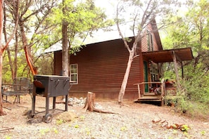 Un chalet rustique doté d’une véranda, d’un barbecue et d’un banc.