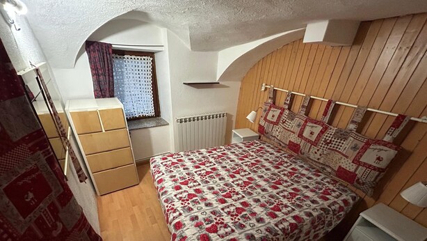 A bedroom with a bed, a window, a radiator, and a wooden wall. - Chalet in the Village of Charvensod - Relaxation and Nature (Charvensod)