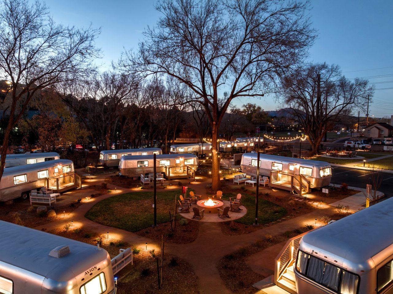 A campground with RVs, a central fire pit area, and a tree in the middle.