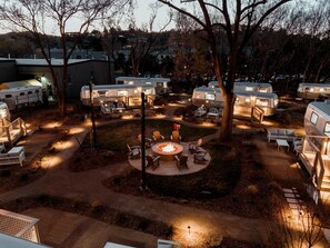 A campsite with RVs, a central fire pit, and outdoor seating.