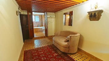 Ein Flur mit einem beige farbenen Sofa, einem gemusterten Teppich, Holzboden und einem kleinen Wanddekor.
