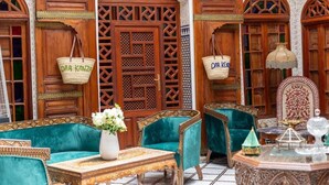 A traditional Moroccan interior with wooden doors, green upholstered sofas, and a patterned table. - Riad Dar Kenza (Fes)