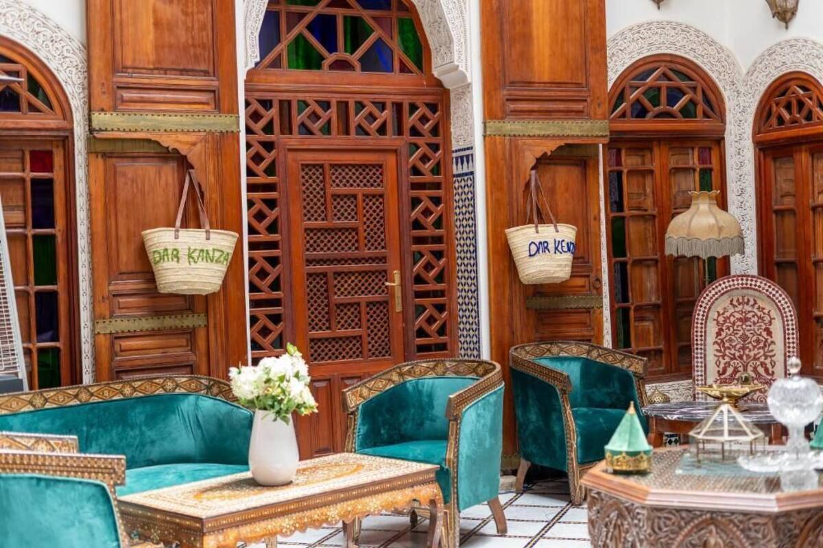 A traditional Moroccan interior with wooden doors, green upholstered sofas, and a patterned table.