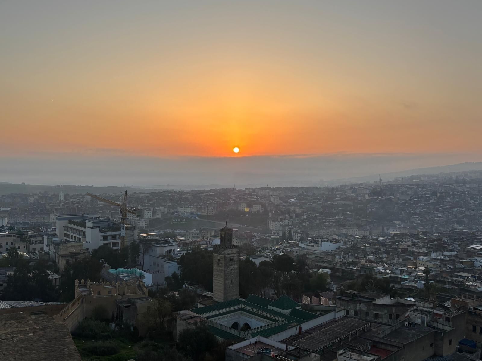 Un paisaje urbano con una torre destacada y un atardecer.