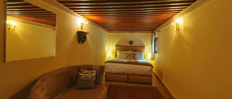 A cozy room with a bed, a sofa, and a patterned rug.