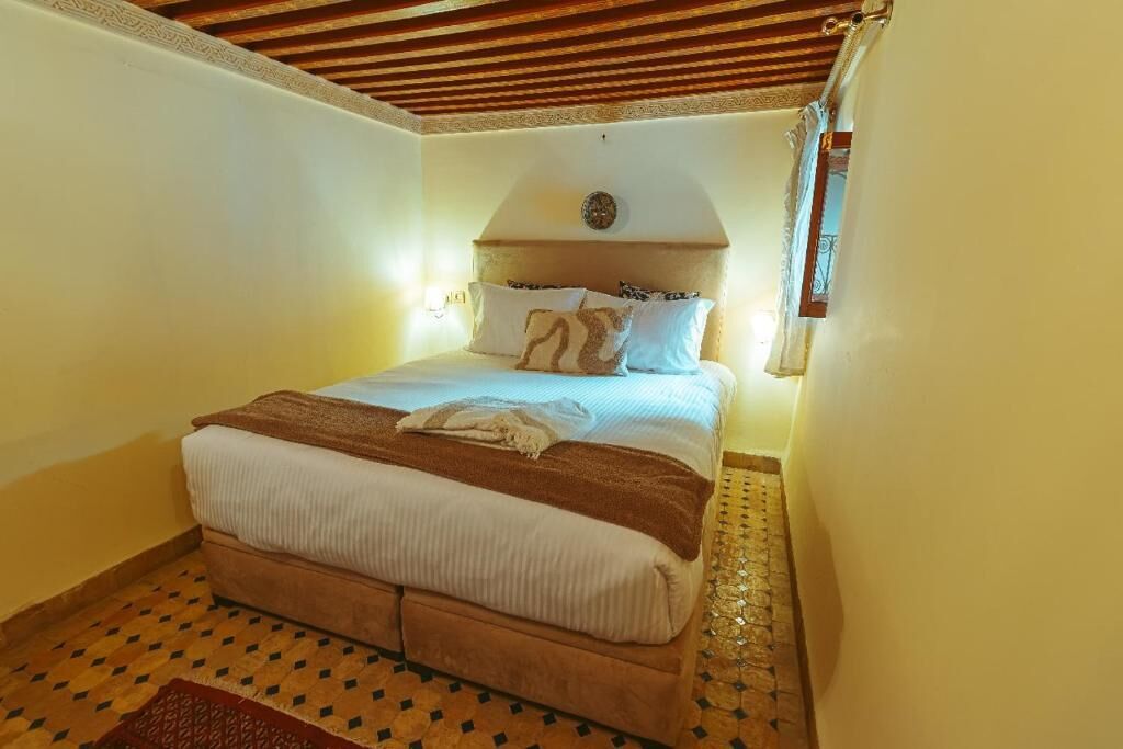 Une chambre à coucher avec un lit, une tête de lit, une horloge murale et un sol à motifs.
