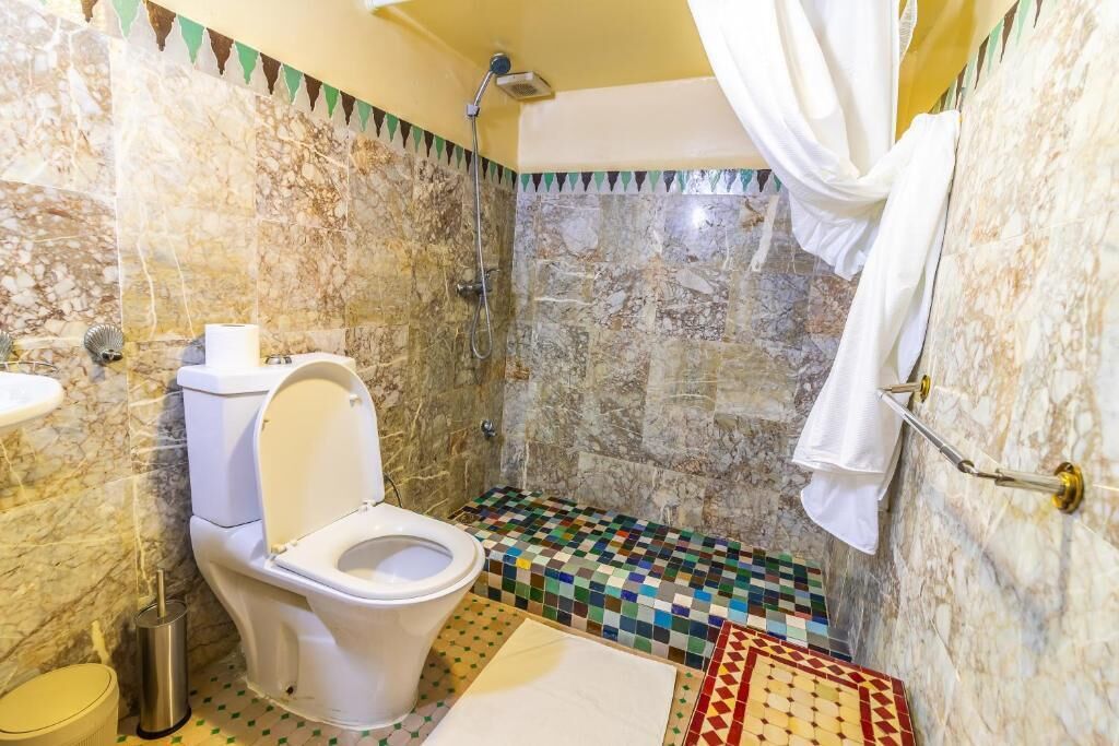 A bathroom with a toilet, shower, and tiled floor.