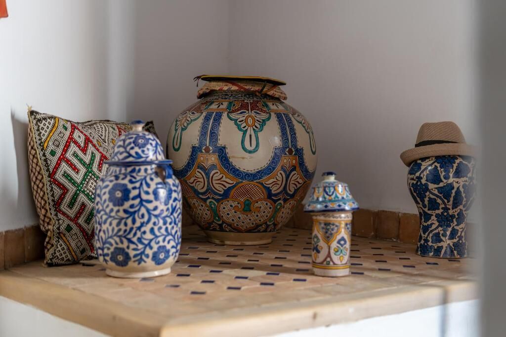 A shelf with various ceramic items including a large vase, a smaller vase, and a decorative pot.