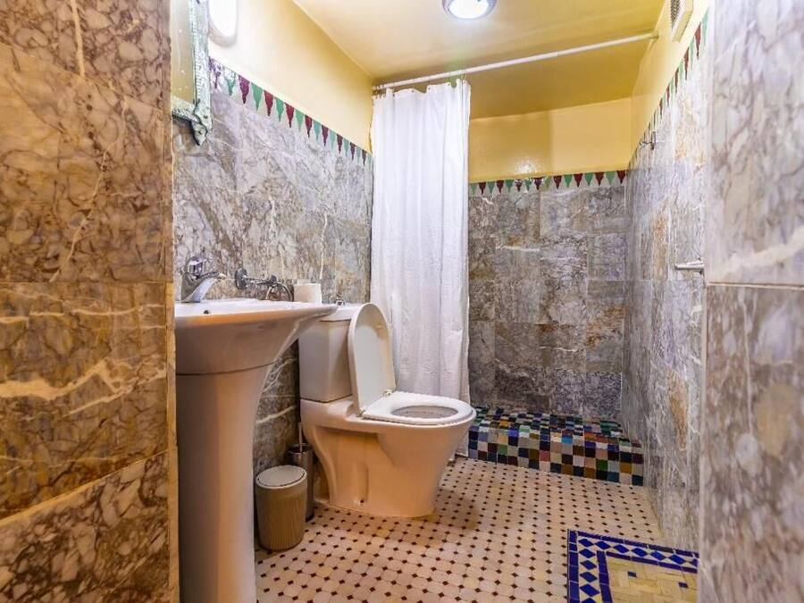 A bathroom with a marble wall, a toilet, a sink, and a shower area.