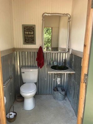 Une petite salle de bain comprenant des toilettes, un lavabo et un miroir.