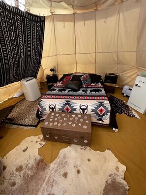 Ein Zeltraum mit Bett, kleinem Tisch, Heizung und einer Aufbewahrungsbox.