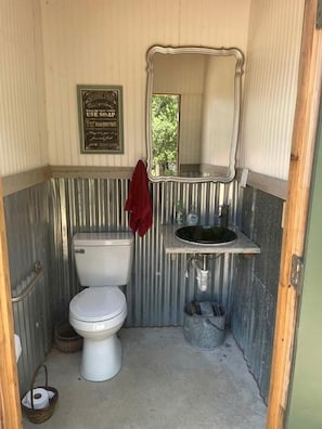 A compact bathroom with a toilet, a sink, and a mirror.