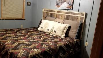 Une chambre à coucher avec une tête de lit en bois, une courtepointe à motifs et un tableau au-dessus du lit.