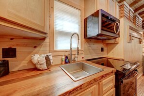 Una cocina de madera con un lavabo, un escurreplatos y un horno empotrado.