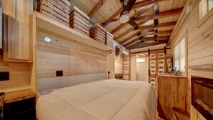 A wooden interior with a large bed, wooden walls, and a ceiling fan. - Appalachian Adventure in this Tiny Cabin near Hiawassee, Ideal for Couples' Glamping (Hayesville)