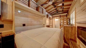 Un interior de madera con una cama grande, paredes de madera y un ventilador de techo.