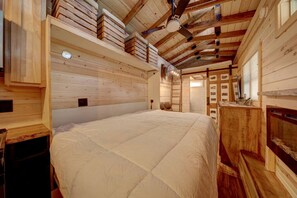 A wooden interior with a large bed, wooden walls, and a ceiling fan. - Appalachian Adventure in this Tiny Cabin near Hiawassee, Ideal for Couples' Glamping (Hayesville)