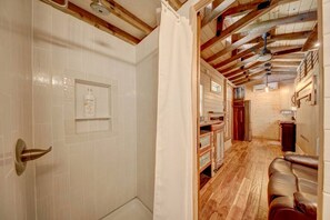 A bathroom with white tiles, a shower, and a wooden ceiling. - Appalachian Adventure in this Tiny Cabin near Hiawassee, Ideal for Couples' Glamping (Hayesville)