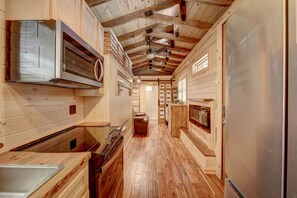 Un interior de madera con una cocina, que incluye una estufa, horno y refrigerador.