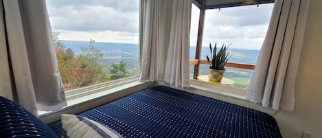Una habitación con cama, ventanas amplias y vistas al exterior.