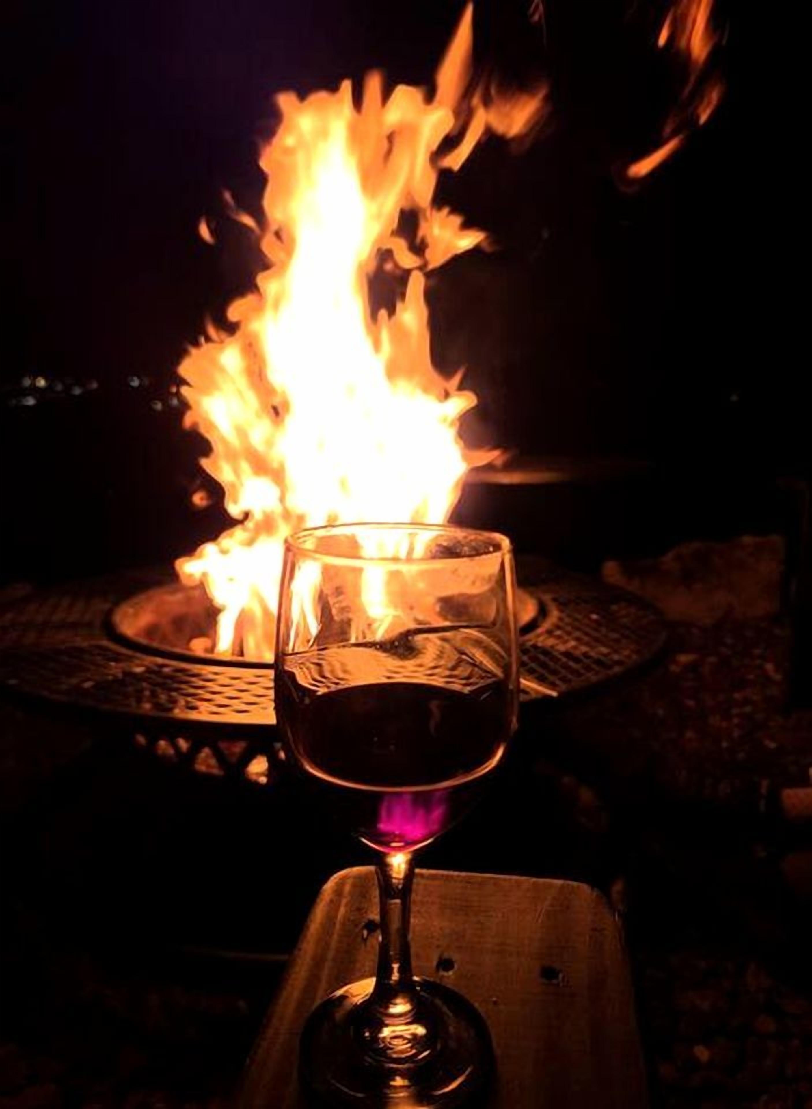 Un verre de vin rouge, avec une flamme en arrière-plan.
