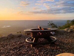 A portable fire pit on a rocky surface with a view of a distant landscape. - Romantic Container Beautifully Design with Deck in Georgia (Rising Fawn)