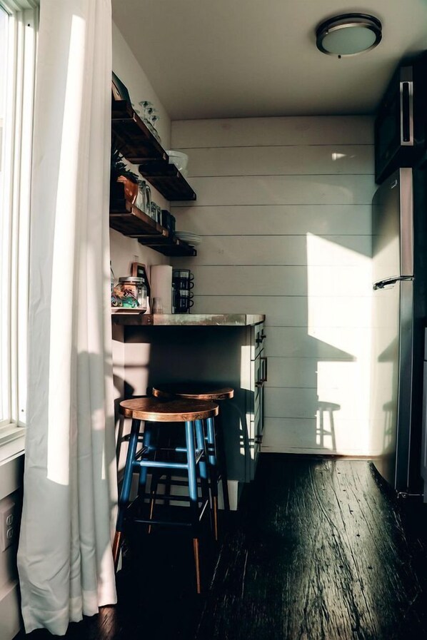A narrow kitchen with wooden walls, a built-in oven, and a window with a curtain. - Romantic Container Beautifully Design with Deck in Georgia (Rising Fawn)