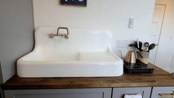 Una cucina con un lavandino bianco, un piano di lavoro in legno e un armadietto con un asciugamano appeso.