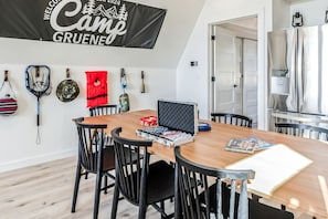 A dining area with a wooden table, black chairs, and a banner on the wall. - Three Stylish A-Frames Perfect for a Group Escape in Texas (New Braunfels)