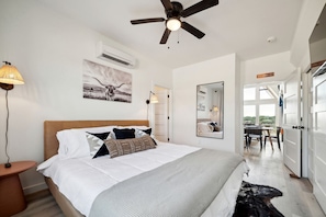 A bedroom with a bed, bedside lamp, ceiling fan, air conditioning unit, and a large mirror. - Three Stylish A-Frames Perfect for a Group Escape in Texas (New Braunfels)