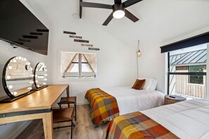 A bedroom with two beds, a vanity with lights, a ceiling fan, a window with a view, and a wall with motivational quotes. - Three Stylish A-Frames Perfect for a Group Escape in Texas (New Braunfels)