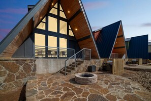 A modern building with a stone foundation, a wooden deck, and a large window.