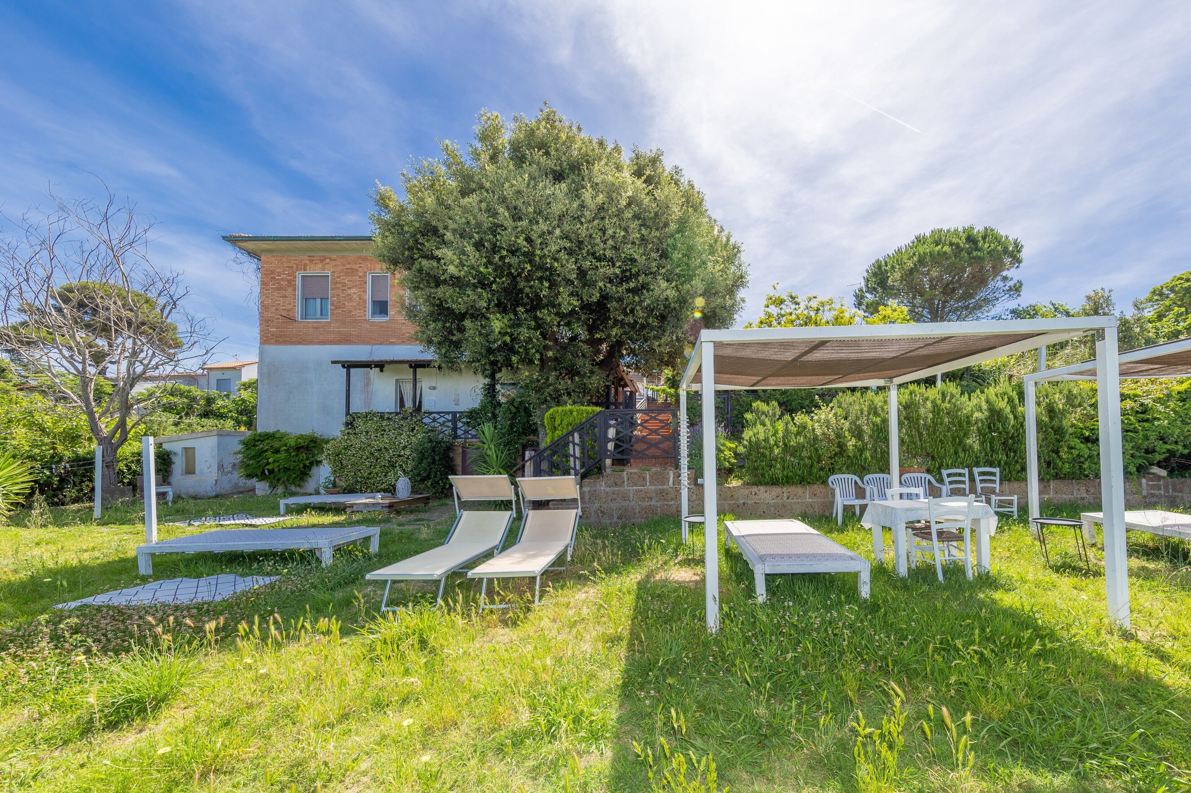 A garden with outdoor seating, a pergola, and a building with a brick facade.