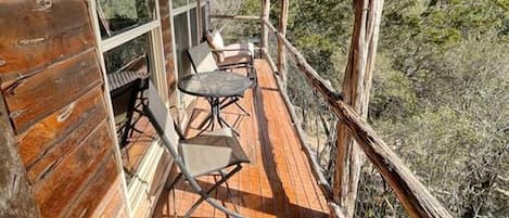 Una cabaña de madera con un porche cubierto, dos sillas y una mesa.