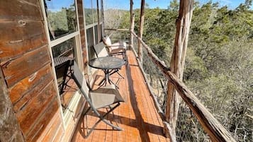 A wooden cabin with a covered porch, two chairs, and a table.
