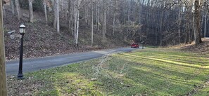 A road with a red car, surrounded by trees and a grassy area.