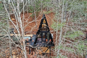 A cabin with a triangular roof, surrounded by trees and a dirt ground. - Intimate Private A-Frame with Spa and Beautiful Outdoor Living in Georgia (Blue Ridge)