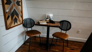 Una piccola zona pranzo con due sedie, un tavolo e un elemento decorativo a parete.