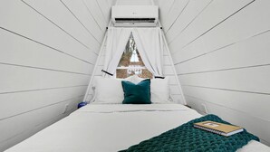 Une chambre avec un lit, une fenêtre donnant sur un beau paysage et un appareil de climatisation.