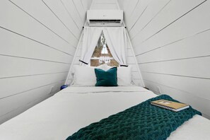 A room with a bed, a window with a view, and an air conditioning unit.