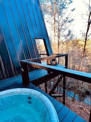 A wooden deck with a hot tub and a wooden chair.