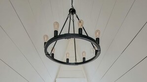 Una stanza stretta con soffitti alti, un letto, un lampadario e una finestra con tende.