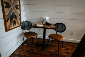 A small dining area with two chairs, a table, and a decorative wall piece.